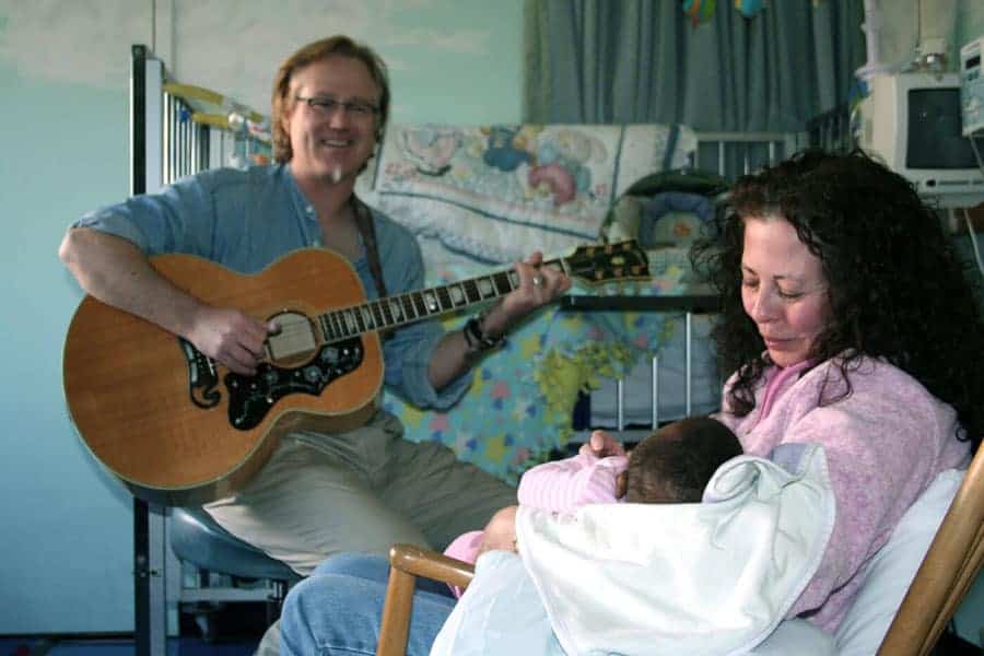 Volunteer rocking a babyas musician plays at The Connecticut Hospice