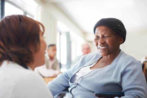 Elderly female cancer patient speaking with her doctor.