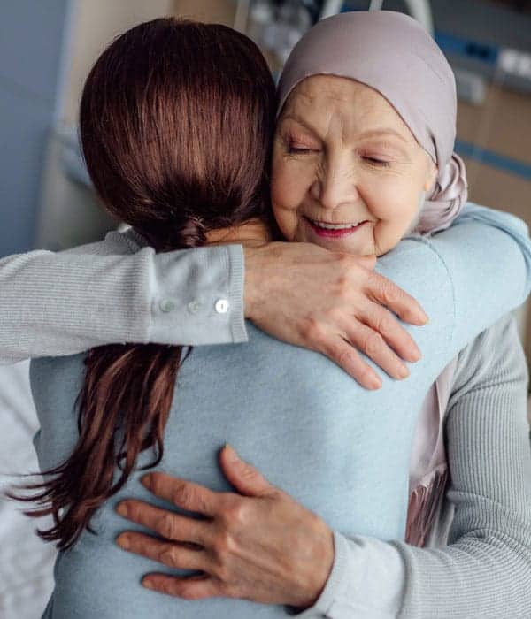 An older female cancer patient higging her daughter