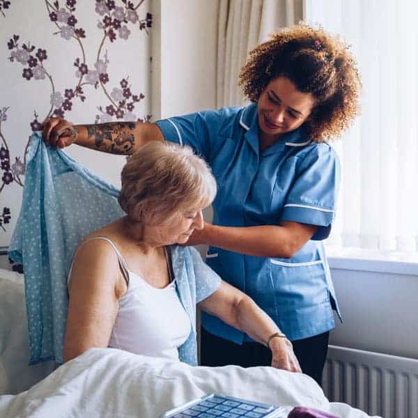 A nurse helping a hospice home care pateint get dressed