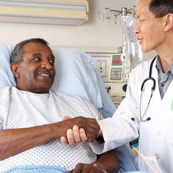 Palliate Care Patient in a Hospital Bed Shakes hands with his doctor