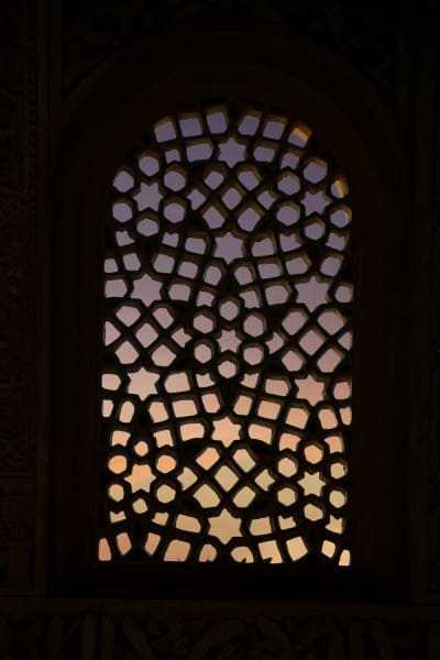 carved mosque window looking out on sunset