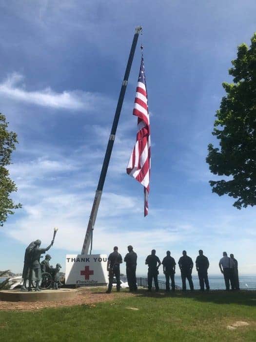 Branford Firemen stand in line near 50 foot flag overlooking the water at Connecticut Hospice