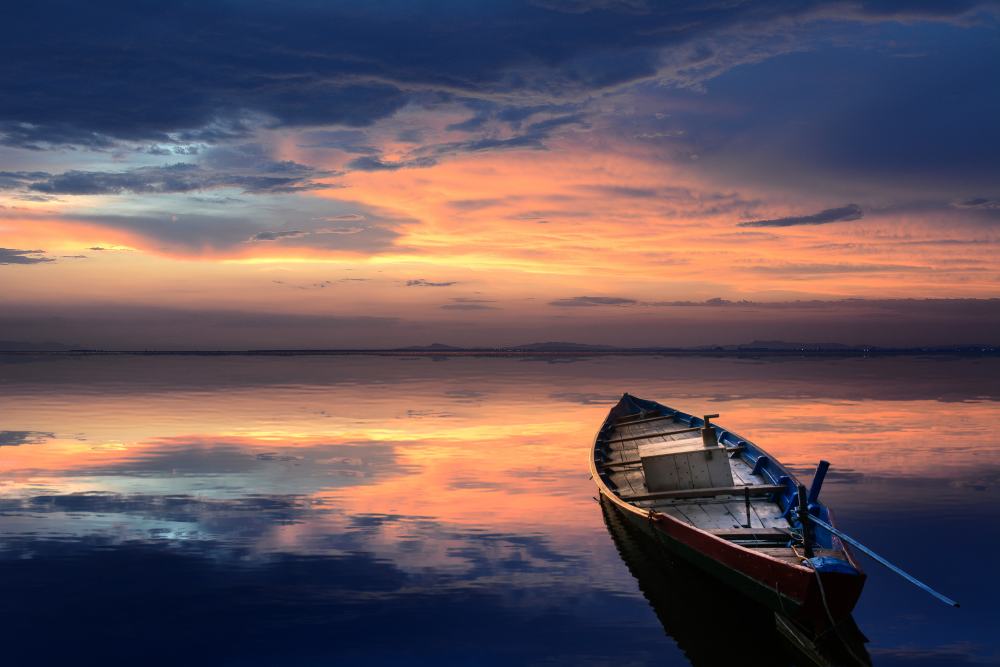 small wooden boat on shore at sunset