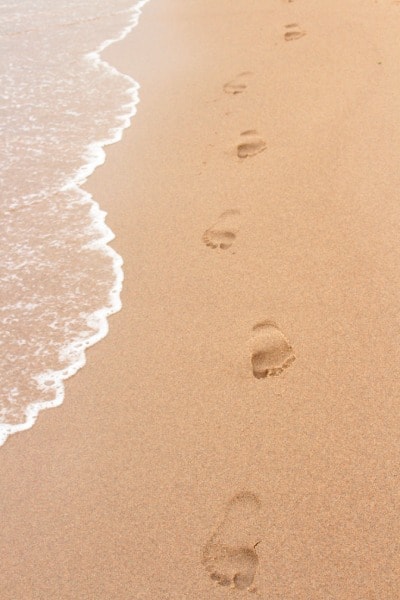 footprints in smooth sand near water's edge