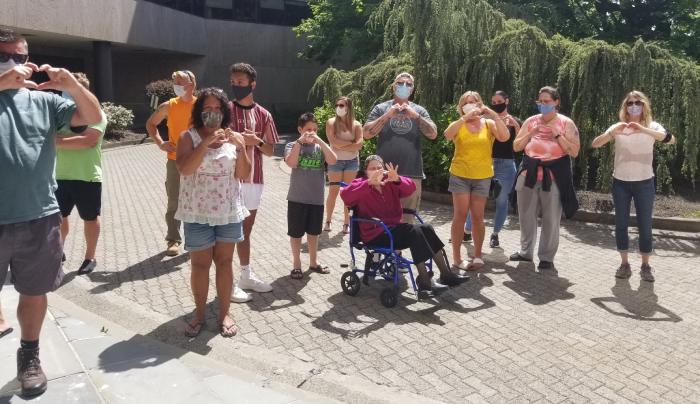 Family members greet ambulance as it arrives at Connecticut Hospice, all making heart shape with hands