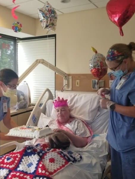 Hospice staff bring ice cream cake to patient sitting up in bed 