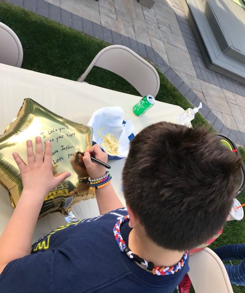 boy pictured from behind writing a message to his dying great-grandfather on a balloon
