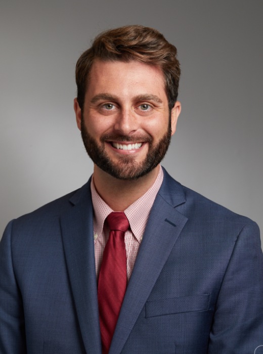 Doctor wearing jacket and tie smiles at camera