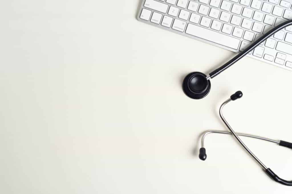 A computer keyboard with a stethoscope draped over it.