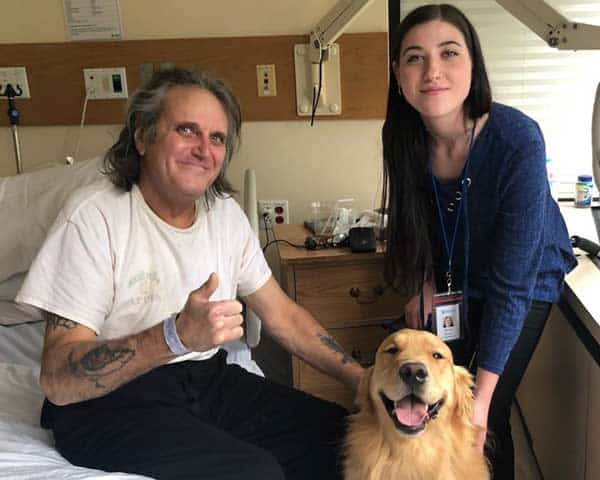 Pet Therapy volunteer brings Golden Retriever to visit a patients bedside