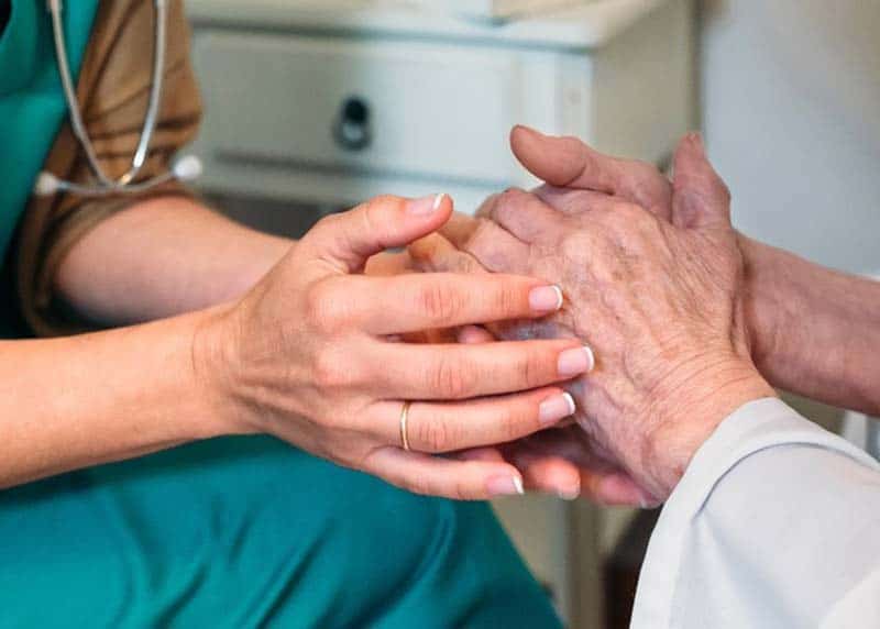 Nurse and female patient joining hands