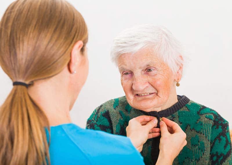 care giver helping elderly patient get dressed