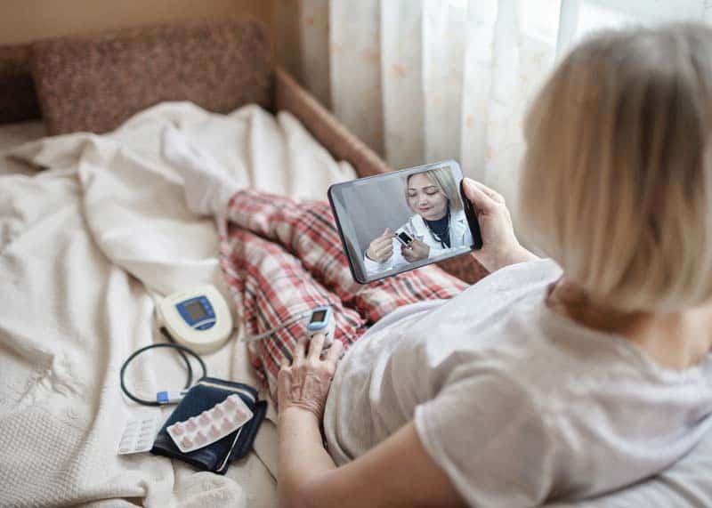 women in hospital bed with doc on cell