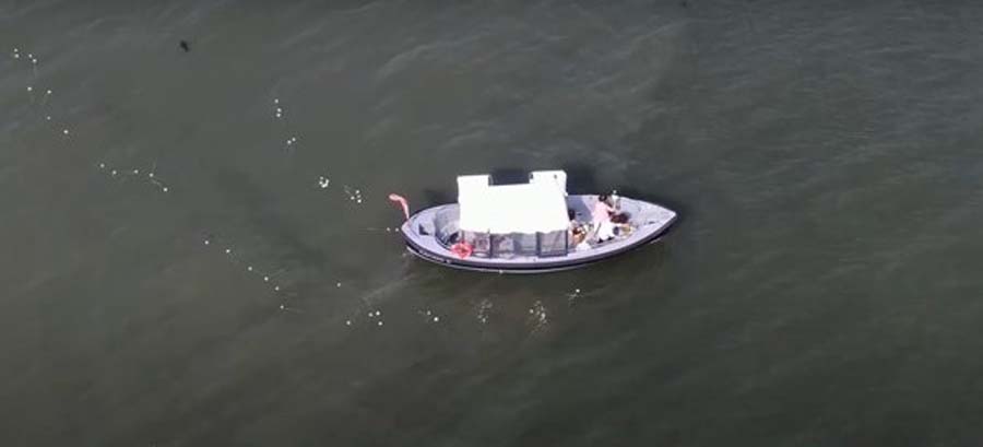 A boat carries flowers out to sea where they are dropped in the water as a tribute