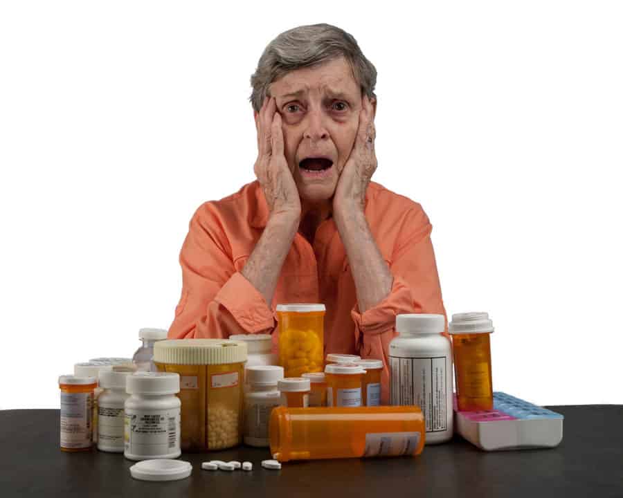 Senior woman overwhelmed by with medications bottles
