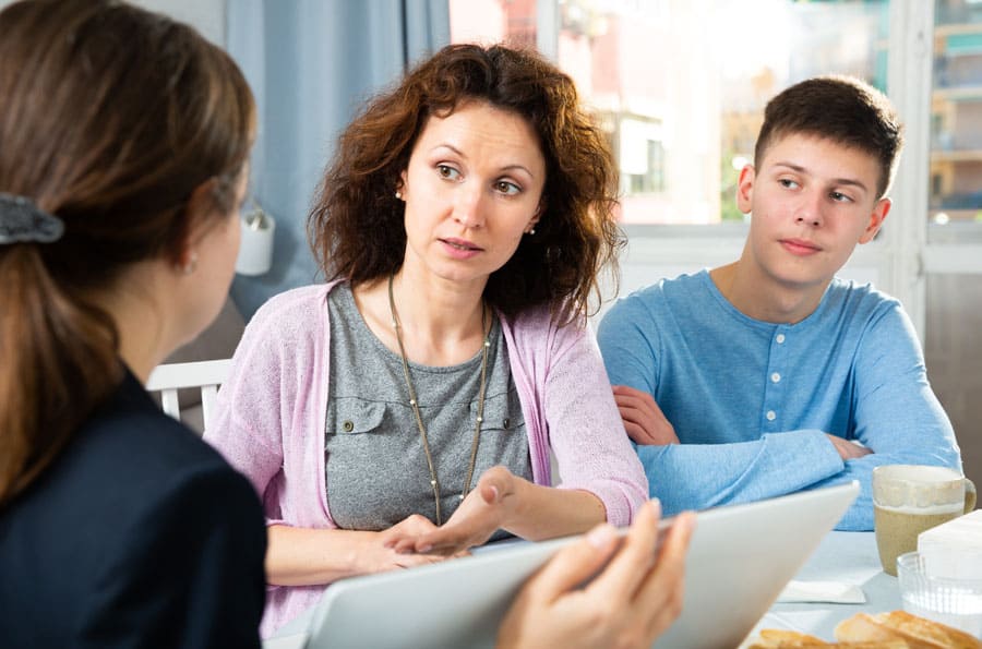 Positive woman with teenager boy discussing documents with a social worker