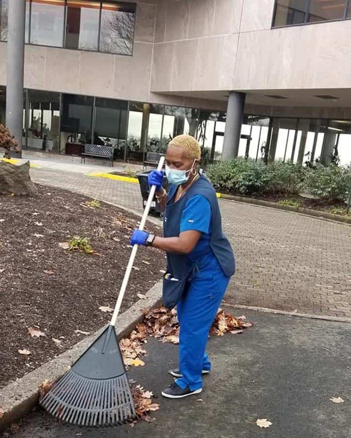 Housekeeping staff member raking leaves
