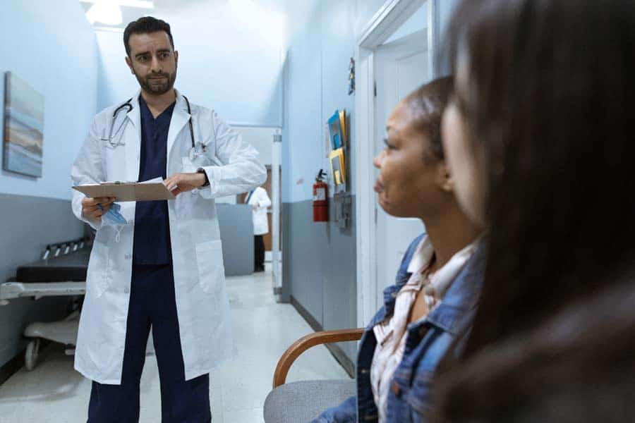 Doctor in hall approaching female waiting patient