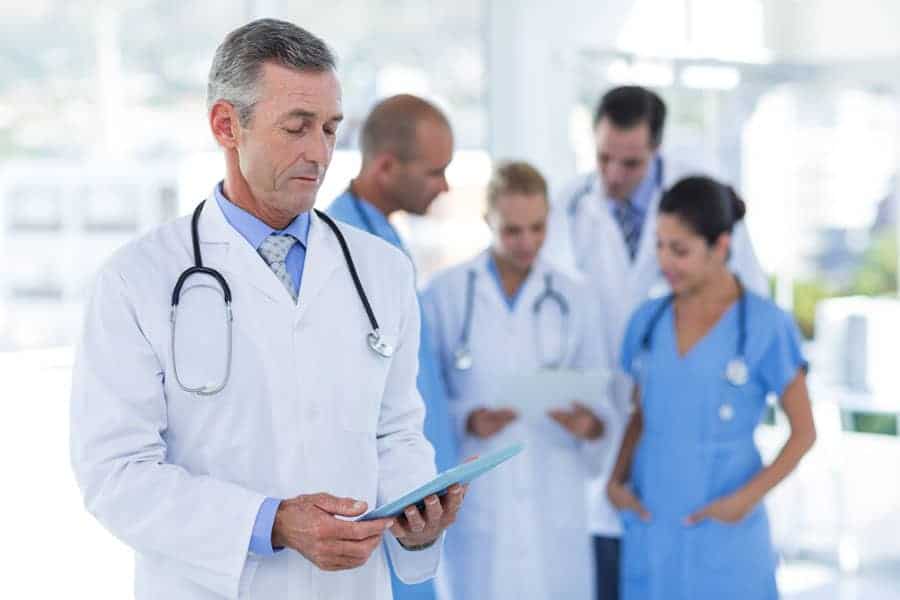Doctor looking at clipboard while his colleague discussing in medical office