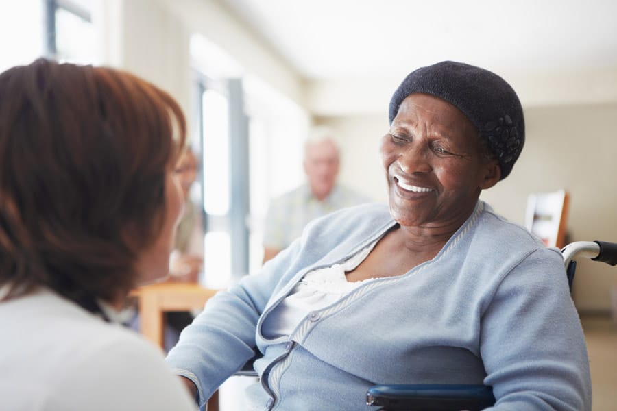 smiling elderly woman in wheel chair speaking with doctor