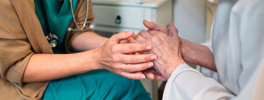 Nurse and female patient joining hands