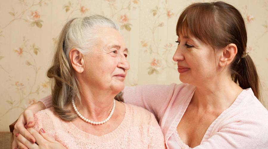 adult daughter with her arms around an elderly mother