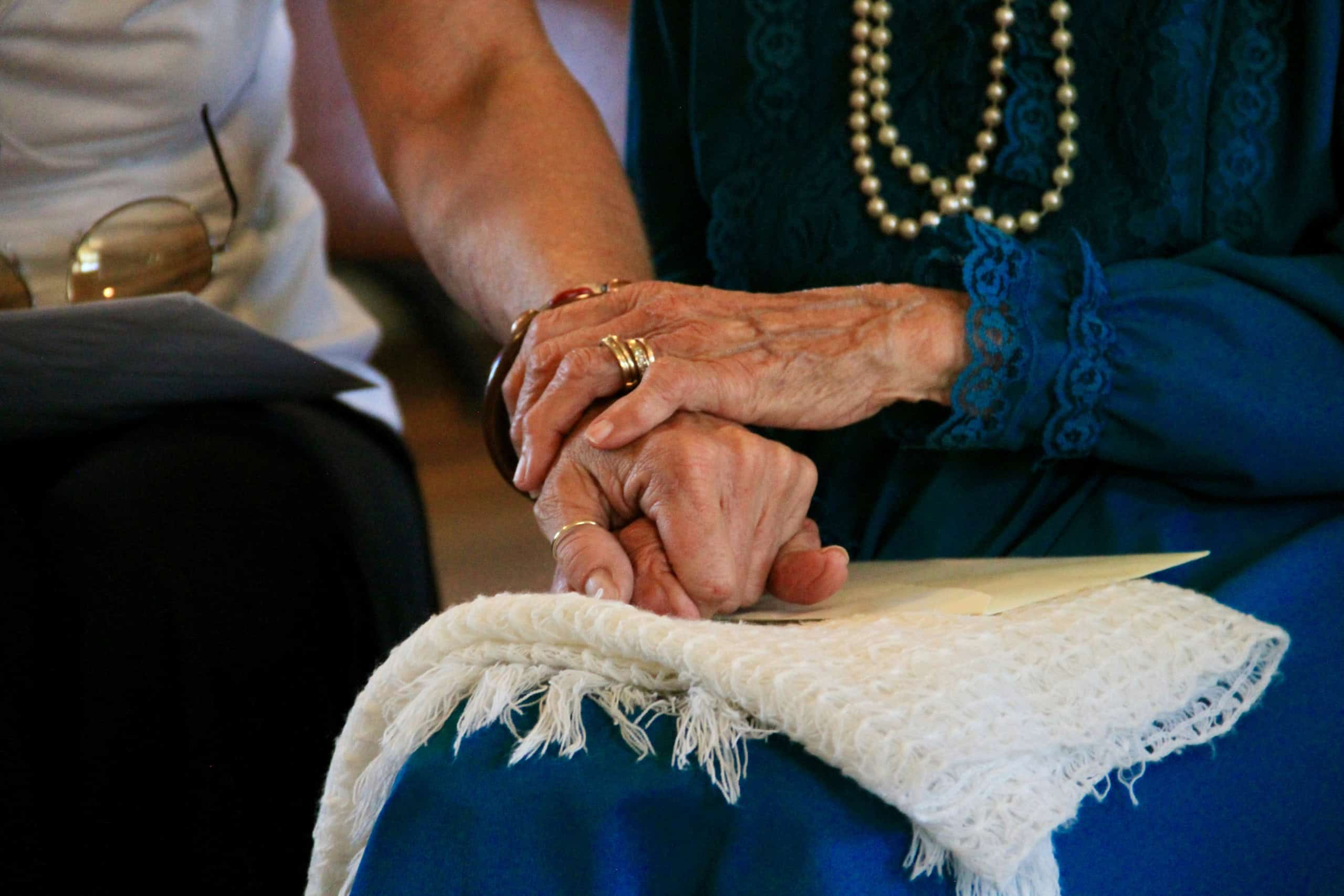 a younger woman and older senior woman holding hands.