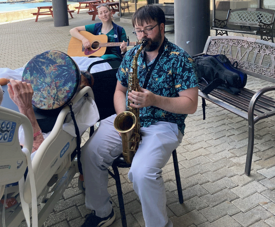 Musicians playing instruments outdoors with a Connecticut Hospice patient