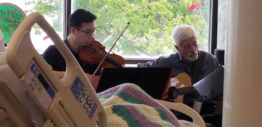 Guitarist and violinist performing at the bedside of Connecticut Hospice patient