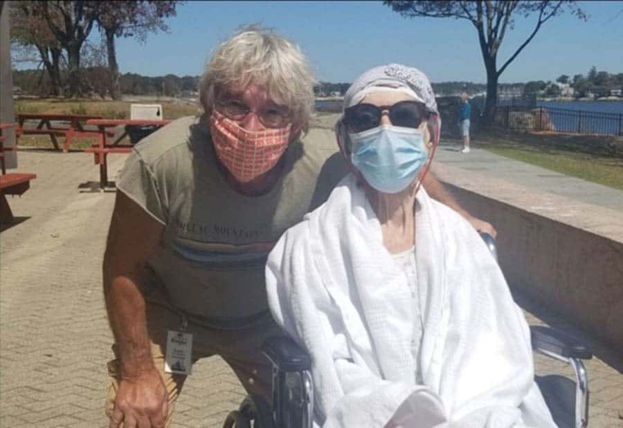 male volunteer pushing patient in wheelchair outside