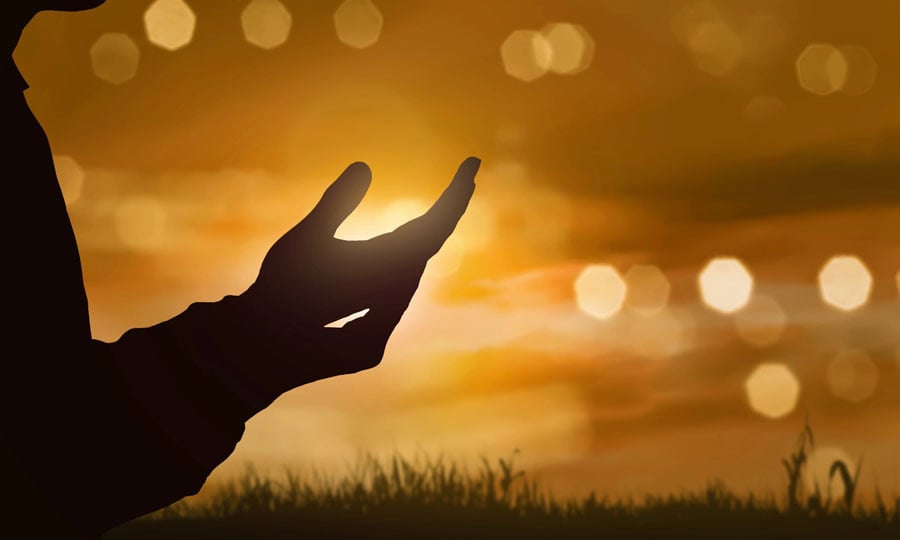 Silhouettes of human hands with open palms at sunset